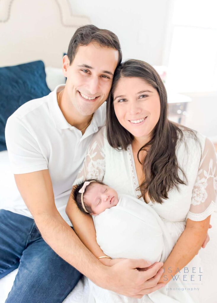 Family with a newborn smiling at the camera.