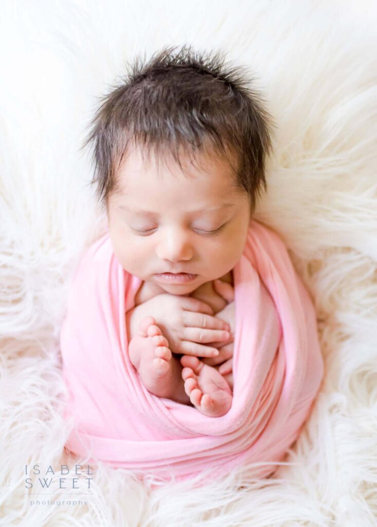 Newborn baby girl with a pink wrap.